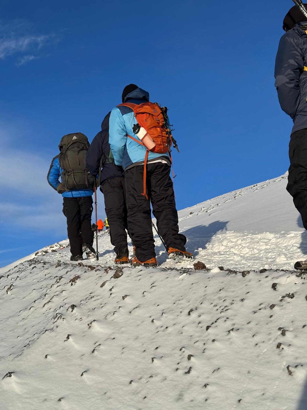 Climbers on the final dawn push along Kilimanjaro's snowy summit ridge