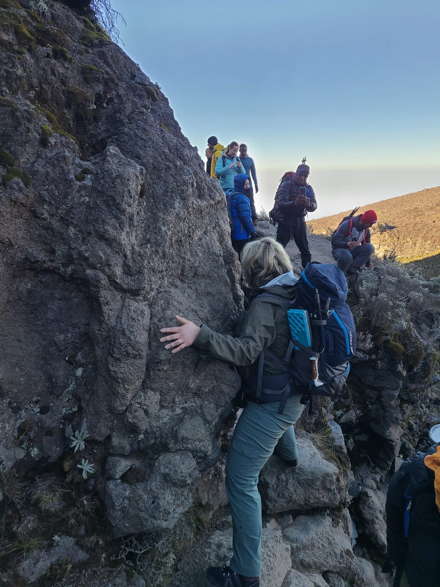 Climbers pausing to touch Kissing Rock on the Barranco section of Mount Kilimanjaro