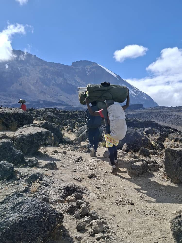 Porters carrying camp equipment toward Barranco with Kibo behind them on Mount Kilimanjaro