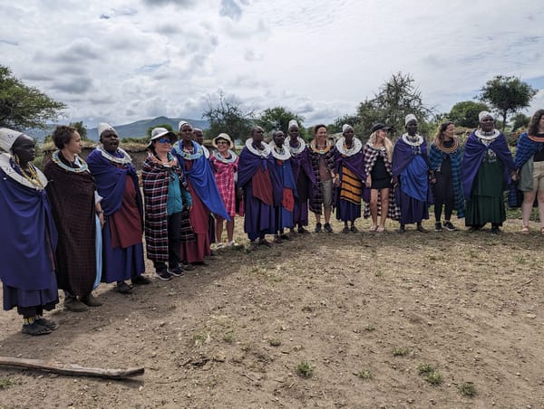 A Maasai welcome circle with visitors and community members in shukas.