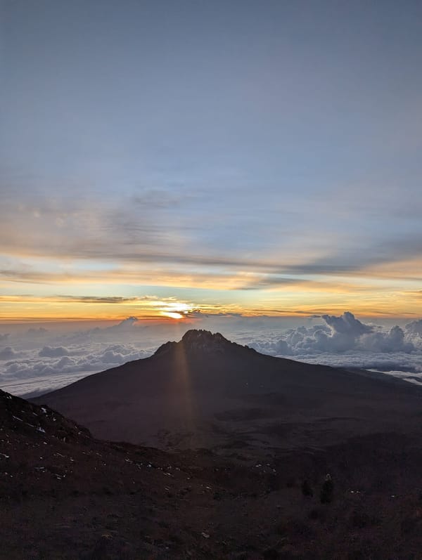 Mawenzi Peak silhouette under a pink dawn sky from the summit zone.