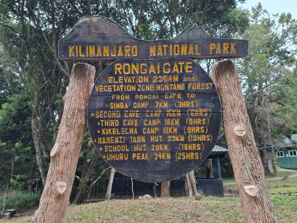 The carved Rongai Gate signboard at 2,364 m, listing every camp distance up to Uhuru Peak.