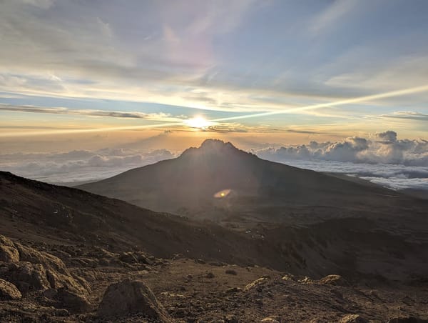 Sunrise with Mawenzi backlit and a wide lens flare across the cloud sea.
