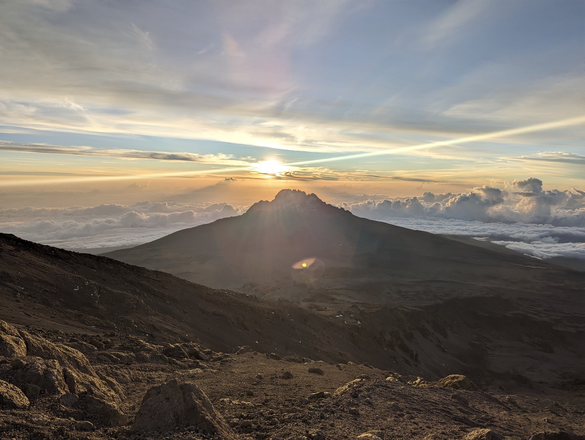 Sunrise with Mawenzi backlit and a wide lens flare across the cloud sea.