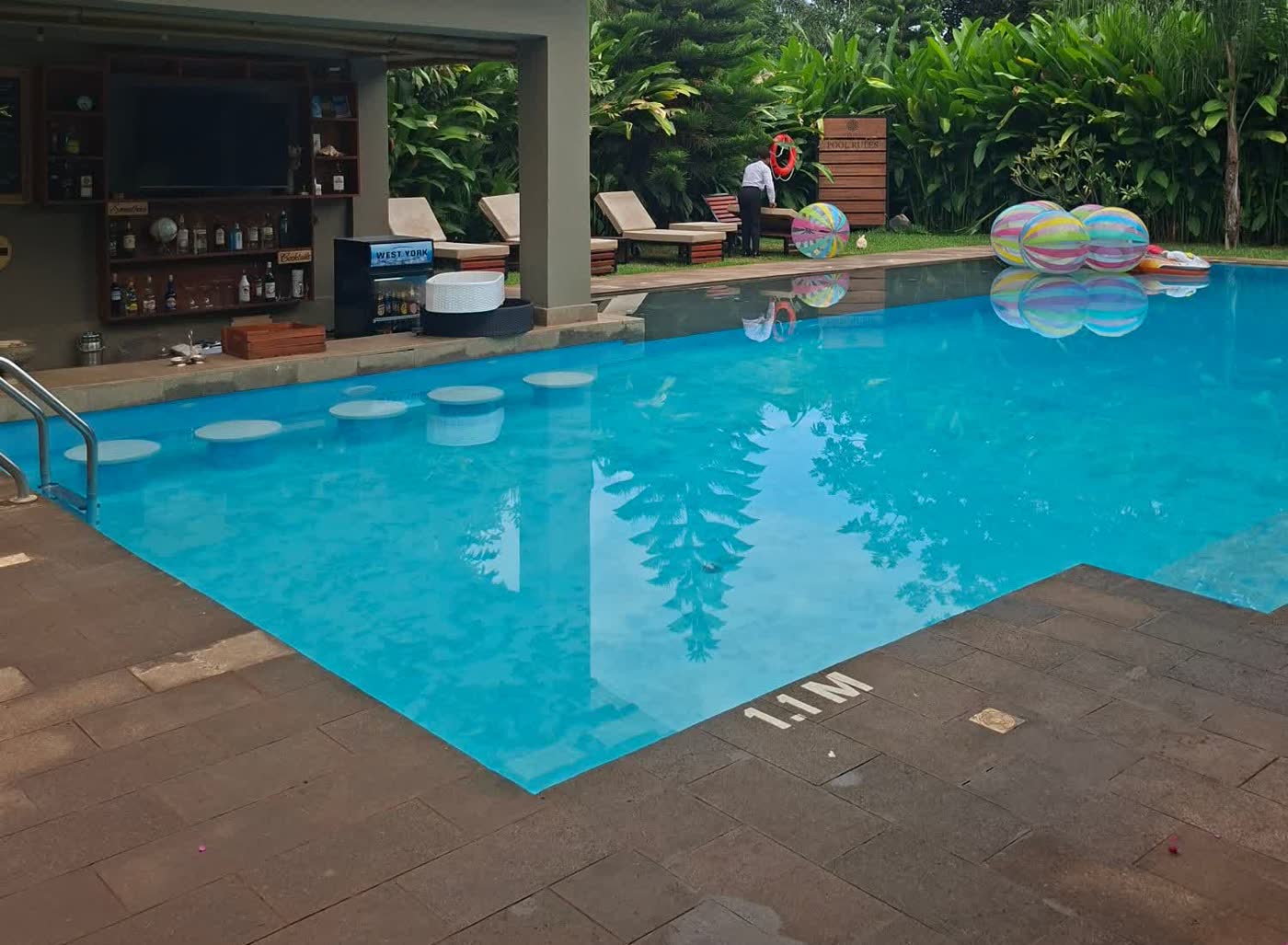 Pool and shaded swim-up bar at the Tulivu retreat in Moshi, sun loungers and tropical garden behind