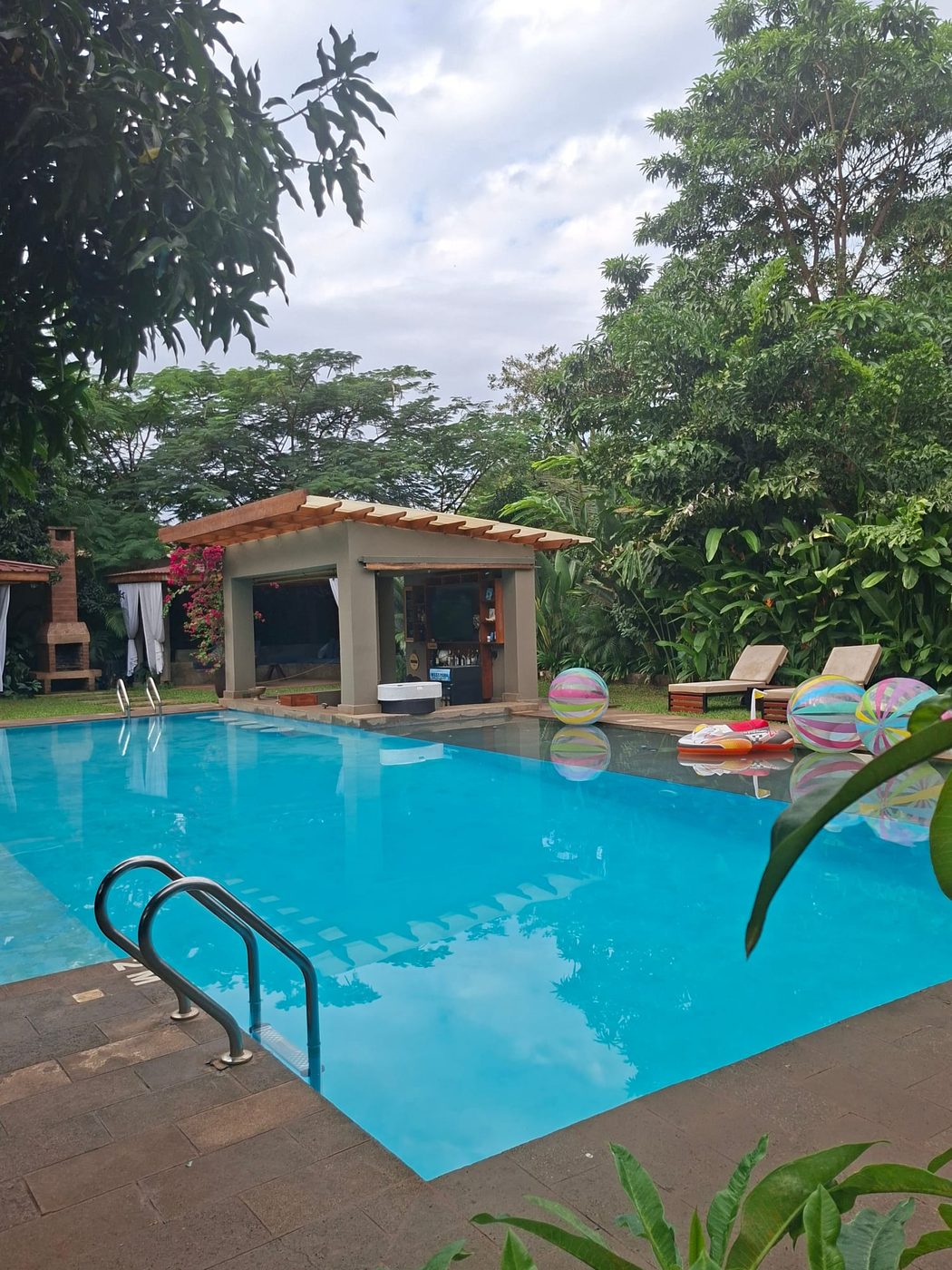 The swimming pool, poolside bar and loungers in the tropical garden of Tulivu guesthouse in Moshi